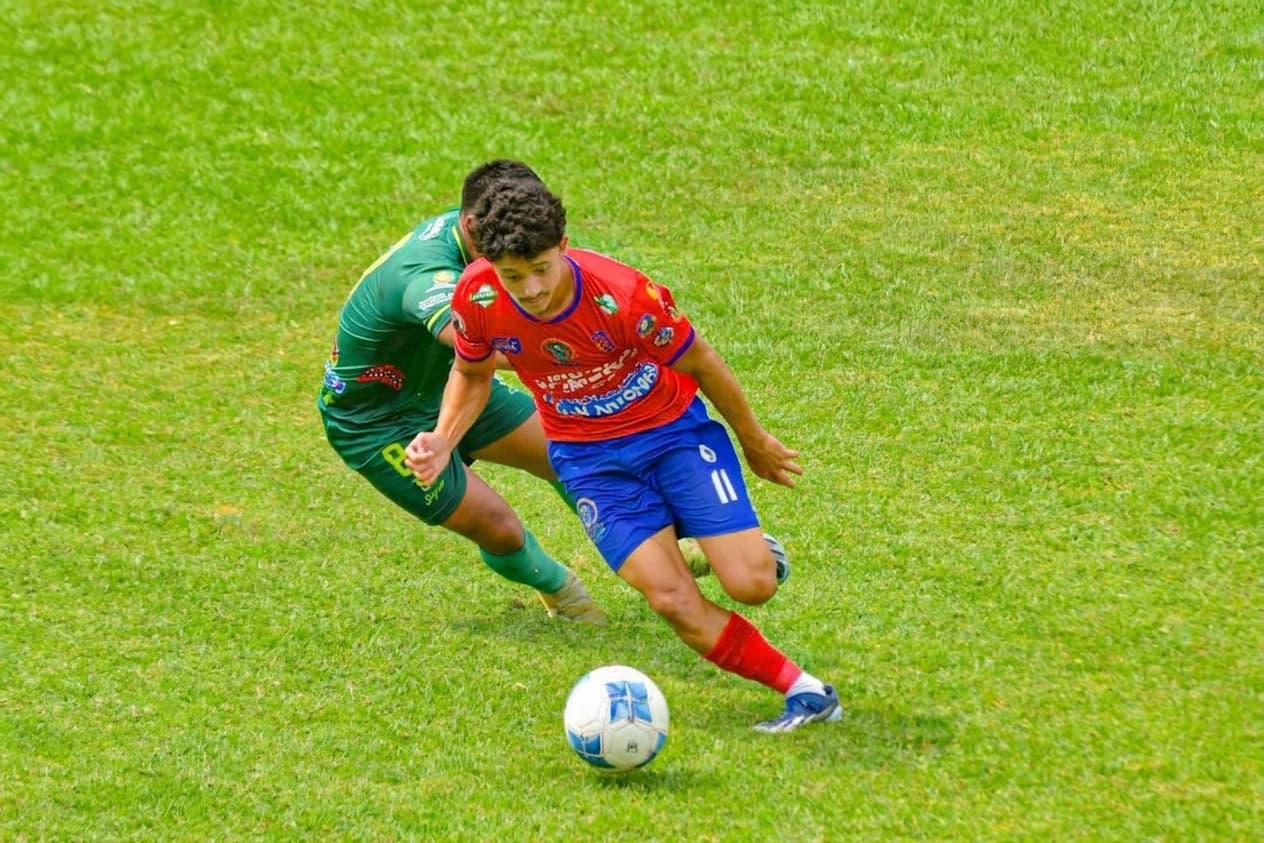 Coach Gabriel Padilla attacking space with the ball in a red jersey.