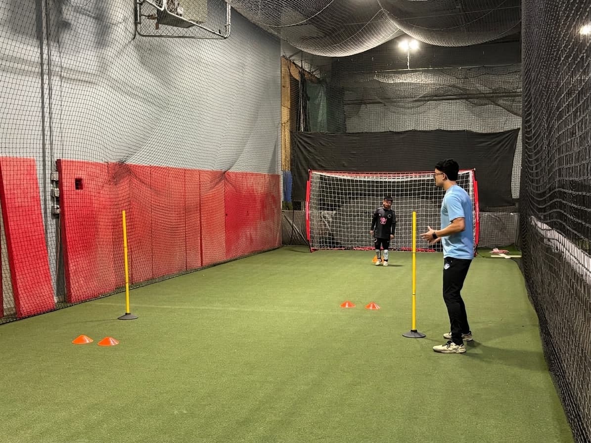 Coach Gabriel Padilla organizing an indoor soccer training drill with cones and poles.