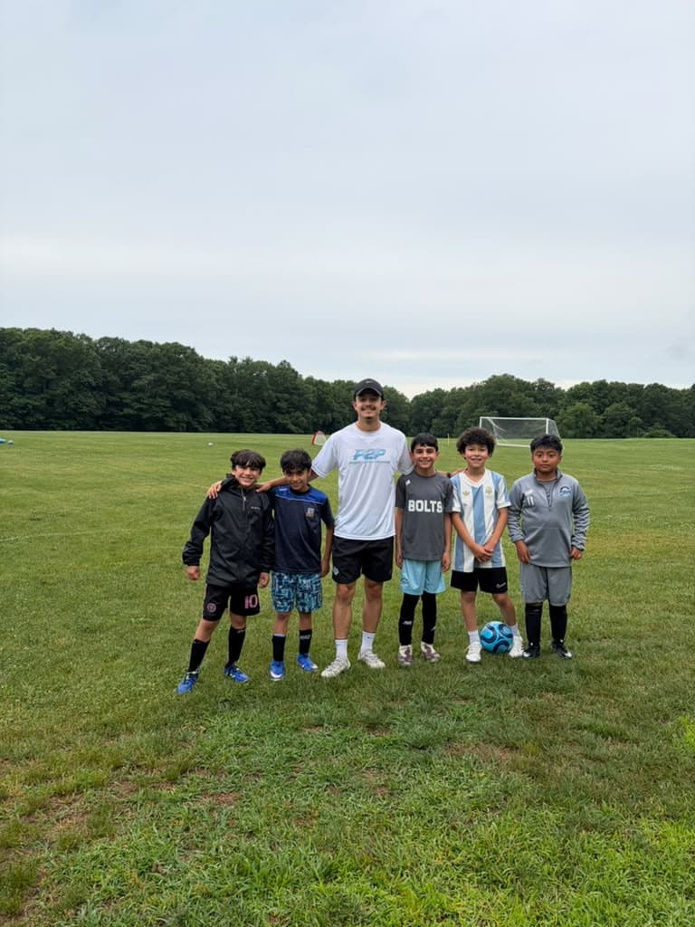 Coach Gabriel with five players during a P2P group session on the soccer field.