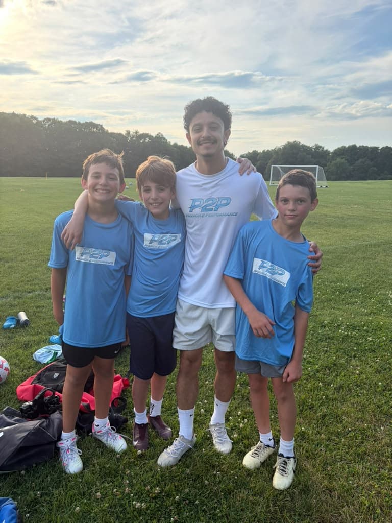 Coach Gabriel with three P2P players on the soccer field.